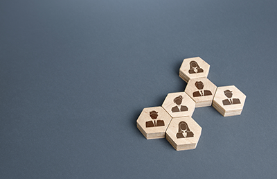 6 hexagonal wooden blocks on a grey background. Each block has a brown stylised image of a person in business clothing 