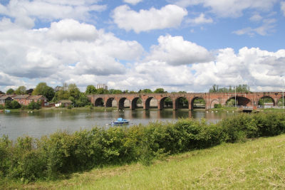 Brick viaduct with grass, hedge row and a river in the foreground
