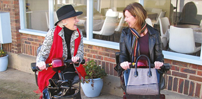 Two people on mobility scooters talking