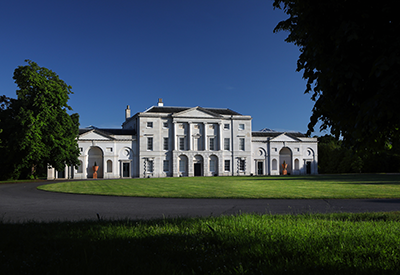 Photo of Cam's Hall a larger mansion with a green lawn in front