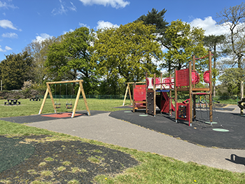 Park Land play area surrounded by trees with blue sky