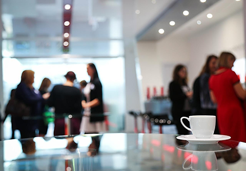 Coffee cup in foreground with business people chatting in background