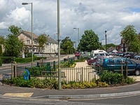 An image of Highlands Road showing the shops on the right hand side, houses on the left hand side and the newly landscaped central parking area in the foreground.