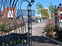 An image of the Market Quay car park showing newly planted trees and flower beds with a metal seat shaped like a crown in the foreground.